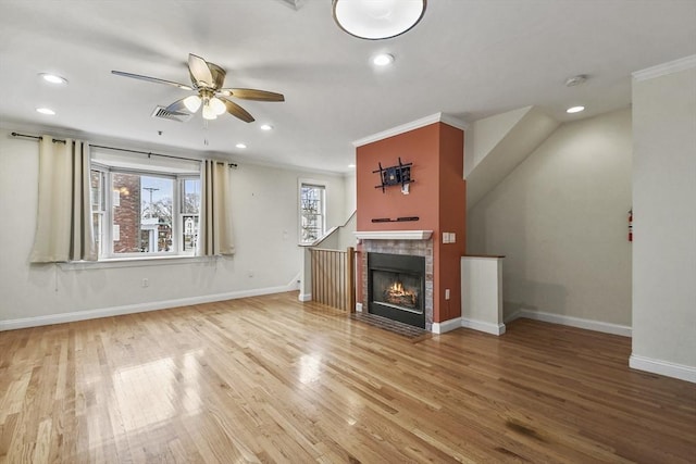 unfurnished living room with hardwood / wood-style flooring, ceiling fan, ornamental molding, and a tiled fireplace