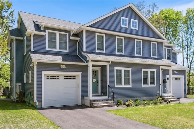 view of front of house with driveway, roof with shingles, a garage, a front lawn, and entry steps
