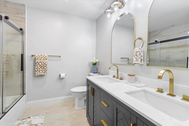 full bath featuring double vanity, a sink, baseboards, and toilet