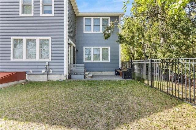rear view of property featuring a lawn, a fenced backyard, and a patio