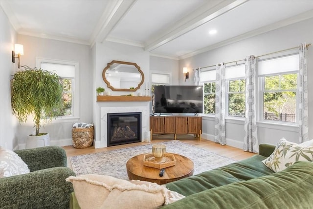 living room with ornamental molding, a glass covered fireplace, wood finished floors, beamed ceiling, and baseboards