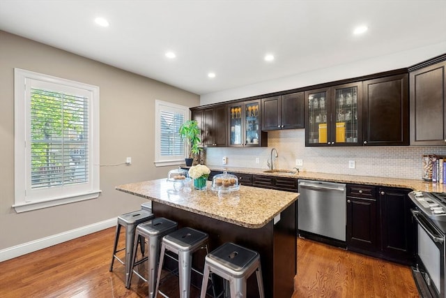 kitchen featuring dishwasher, a sink, black range with electric cooktop, a kitchen breakfast bar, and plenty of natural light