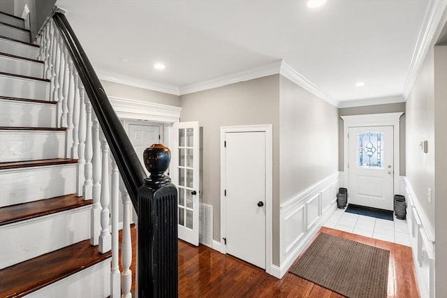 entrance foyer with wood finished floors, ornamental molding, stairway, a wainscoted wall, and recessed lighting