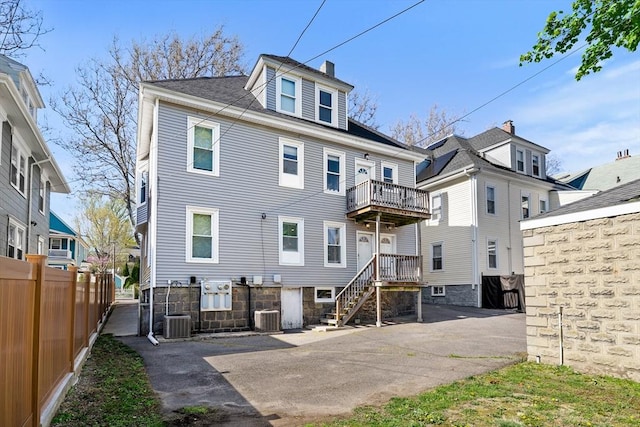 rear view of property featuring fence, central AC unit, and a chimney