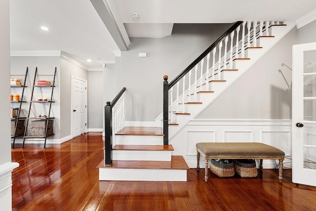 stairway featuring wood finished floors, ornamental molding, wainscoting, and recessed lighting