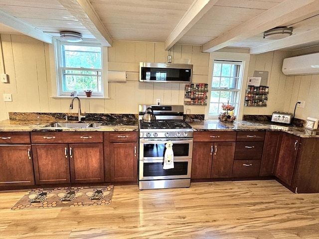 4 Randall Rd, Mattapoisett, MA 02739 - kitchen with stainless steel appliances, a sink, light wood finished floors, dark stone countertops, and wood walls