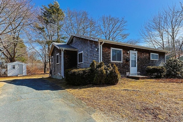 view of front facade featuring aphalt driveway, a storage shed, and an outdoor structure