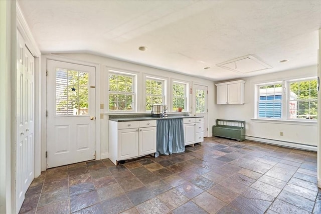 127 Main St, Norwell, MA 02061 - kitchen featuring baseboard heating, white cabinetry, stone tile flooring, lofted ceiling, and baseboards