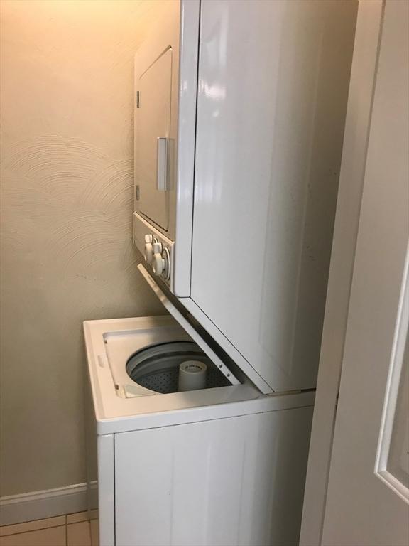 1 Millbrook Ln Unit 201, Wakefield, MA 01880 - laundry room featuring stacked washer / dryer and light tile patterned flooring