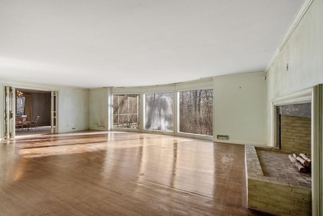 unfurnished living room with wood-type flooring and ornamental molding