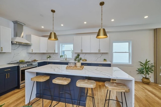 18 Belknap St Unit 2, Arlington, MA 02474 - kitchen featuring gas range, wall chimney range hood, white cabinets, decorative backsplash, and a breakfast bar