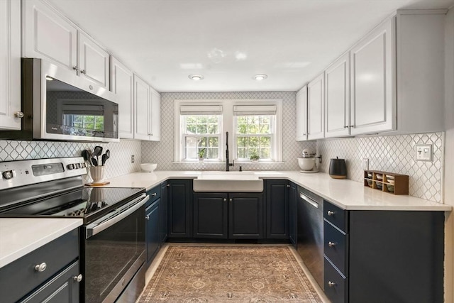 271 Haverhill St, North Reading, MA 01864 - kitchen with appliances with stainless steel finishes, white cabinetry, tasteful backsplash, a sink, and light countertops