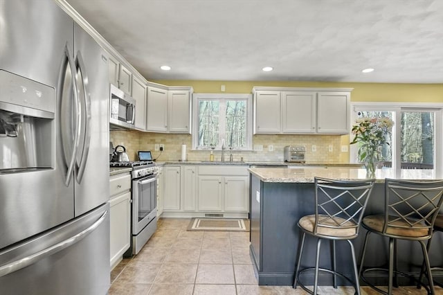 15 Whitewood Cir, Amesbury, MA 01913 - kitchen featuring a sink, backsplash, light stone counters, a breakfast bar, and appliances with stainless steel finishes