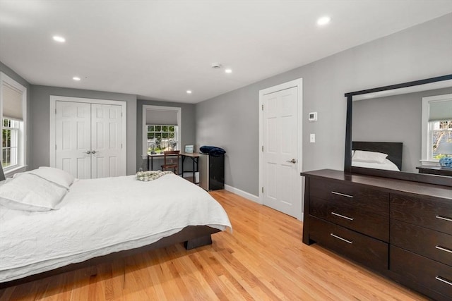 bedroom with light wood-style floors, recessed lighting, baseboards, and a closet