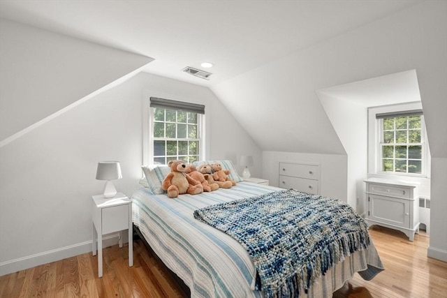 bedroom with lofted ceiling, multiple windows, light wood-style floors, radiator, and baseboards