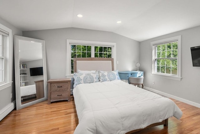 bedroom with a baseboard radiator, vaulted ceiling, light wood-style floors, multiple windows, and baseboards
