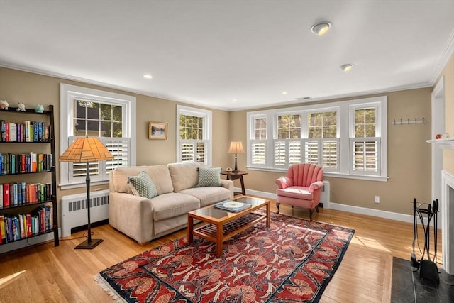 living room featuring radiator heating unit, ornamental molding, plenty of natural light, baseboards, and wood finished floors