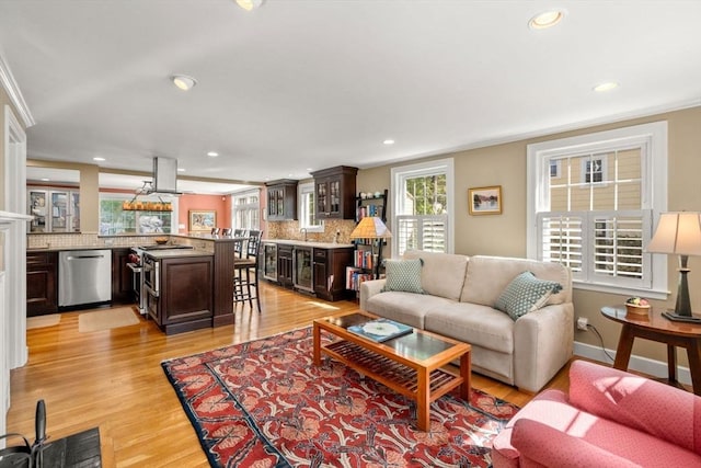 living area featuring crown molding, recessed lighting, light wood-style floors, wine cooler, and bar