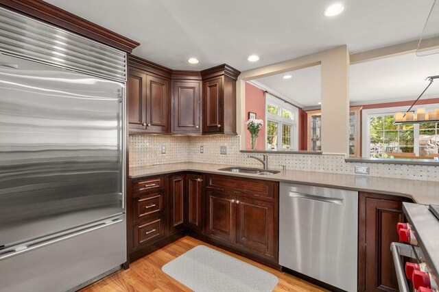 kitchen with appliances with stainless steel finishes, a sink, plenty of natural light, light wood finished floors, and recessed lighting