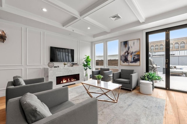 living room featuring hardwood / wood-style floors, beam ceiling, coffered ceiling, a fireplace, and french doors