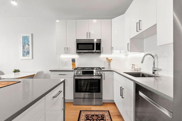 kitchen with stainless steel appliances, white cabinetry, sink, and tasteful backsplash