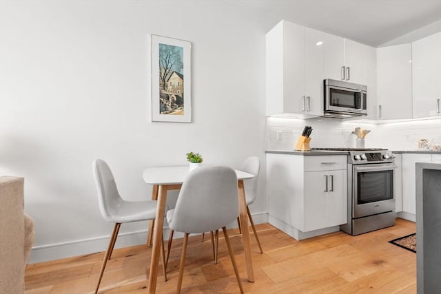 kitchen featuring white cabinetry, backsplash, light hardwood / wood-style flooring, and appliances with stainless steel finishes