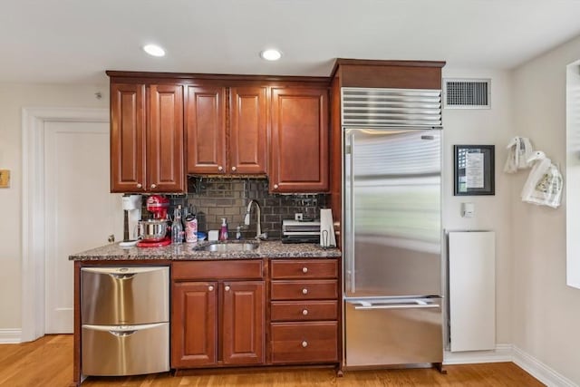 20 Chapel St Unit B811, Brookline, MA 02446 - kitchen featuring stainless steel built in fridge, a sink, dark stone counters, light wood-type flooring, and baseboards
