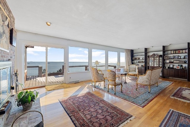 living room with a water view, a healthy amount of sunlight, and light hardwood / wood-style flooring