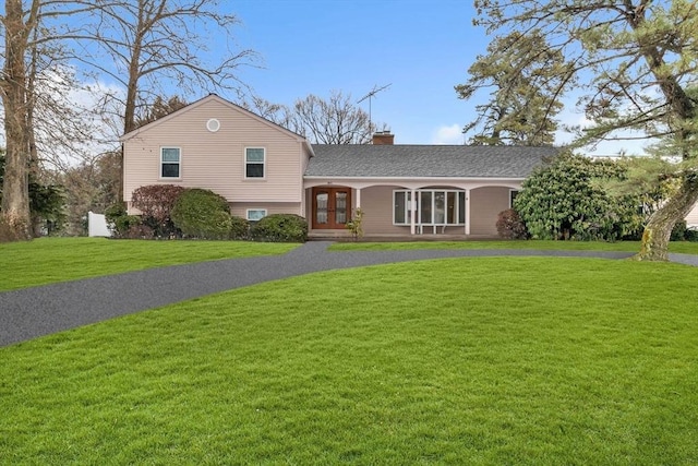 split level home with driveway, a chimney, roof with shingles, french doors, and a front yard