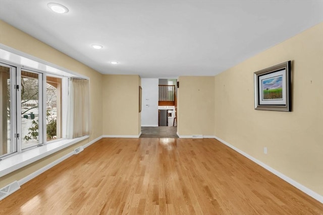 unfurnished living room featuring light wood finished floors, visible vents, and baseboards