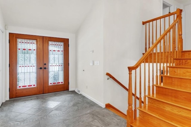 foyer entrance featuring stairway, baseboards, vaulted ceiling, and french doors