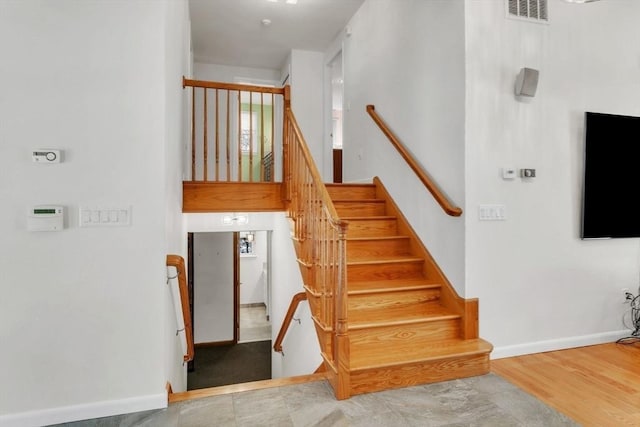 stairs with baseboards, visible vents, and wood finished floors