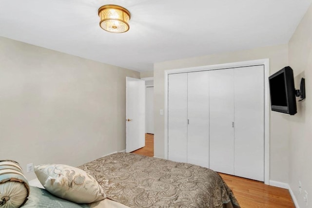 bedroom with light wood-type flooring, a closet, and baseboards