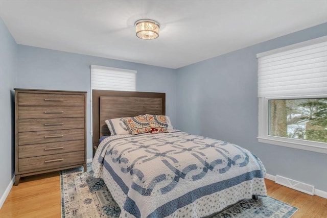 bedroom featuring light wood-style flooring, visible vents, and baseboards