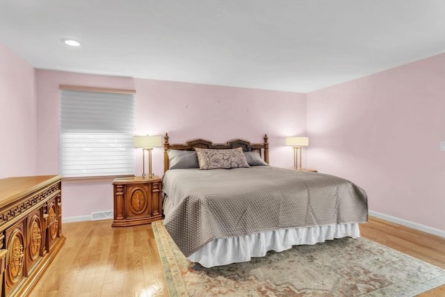 bedroom featuring baseboards, visible vents, and light wood finished floors