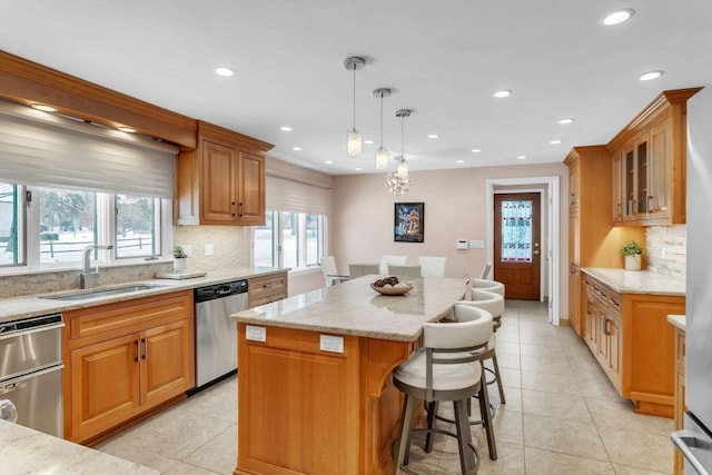 kitchen featuring dishwasher, glass insert cabinets, a center island, hanging light fixtures, and a sink