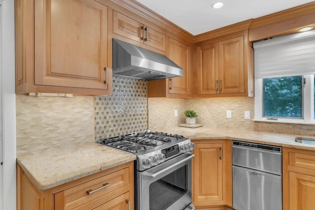 kitchen featuring tasteful backsplash, stainless steel appliances, wall chimney range hood, and light stone countertops