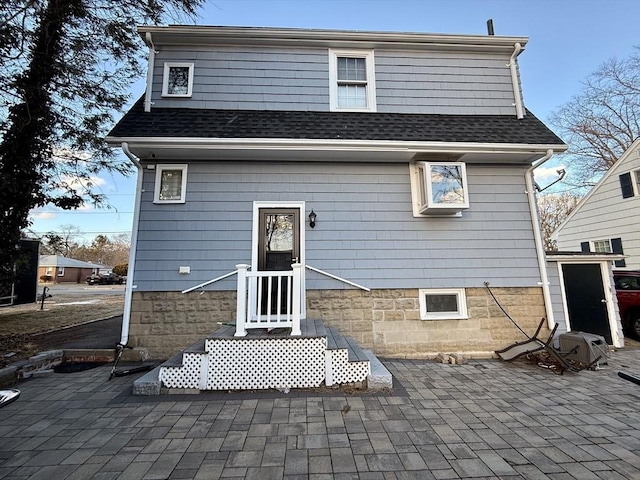 rear view of property featuring a patio and roof with shingles