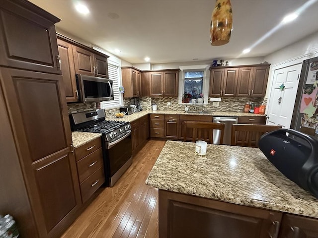 kitchen featuring light wood-type flooring, tasteful backsplash, appliances with stainless steel finishes, and a sink