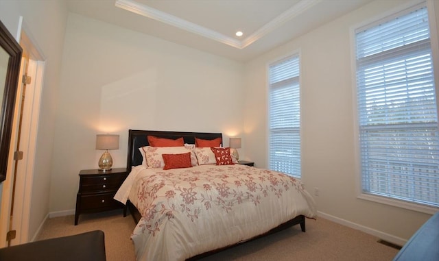 carpeted bedroom featuring a raised ceiling and ornamental molding