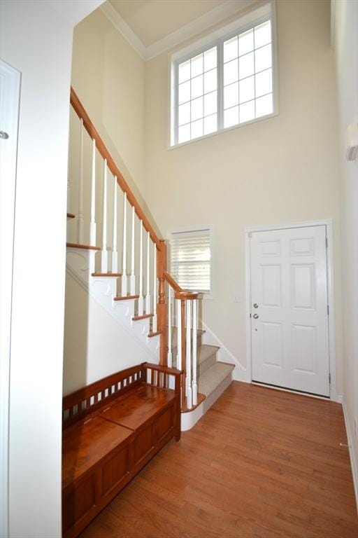 foyer entrance featuring hardwood / wood-style floors, a high ceiling, and ornamental molding