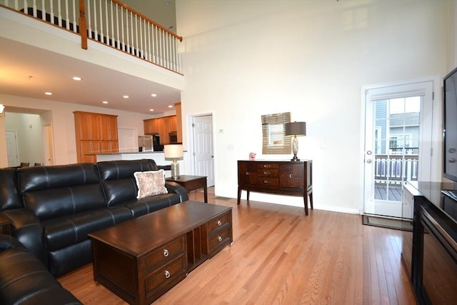 living room featuring light hardwood / wood-style flooring and a towering ceiling