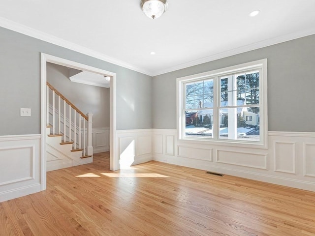 spare room with crown molding and light wood-type flooring