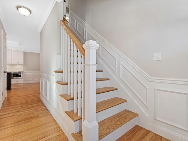 staircase with wood-type flooring and crown molding