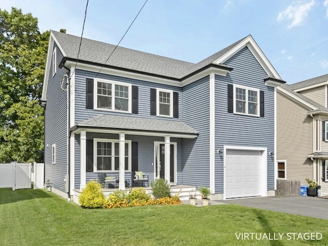 view of front of property featuring a front lawn, covered porch, and a garage