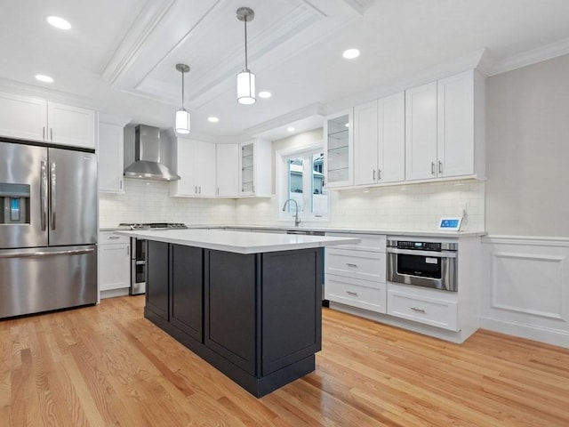 kitchen with white cabinetry, wall chimney range hood, pendant lighting, appliances with stainless steel finishes, and light wood-type flooring