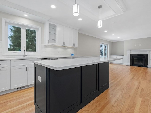 kitchen featuring a center island, sink, hanging light fixtures, light hardwood / wood-style floors, and white cabinetry