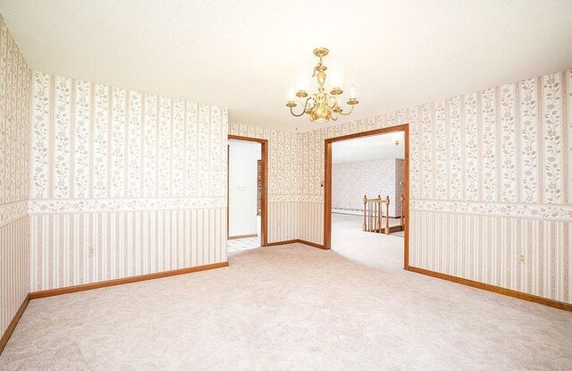 spare room featuring carpet, a chandelier, and wallpapered walls