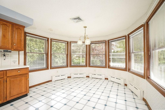 unfurnished sunroom with a baseboard radiator, a wealth of natural light, a baseboard heating unit, and visible vents