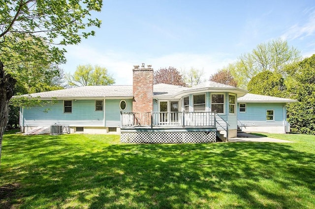 rear view of house with central air condition unit, a wooden deck, a chimney, and a yard